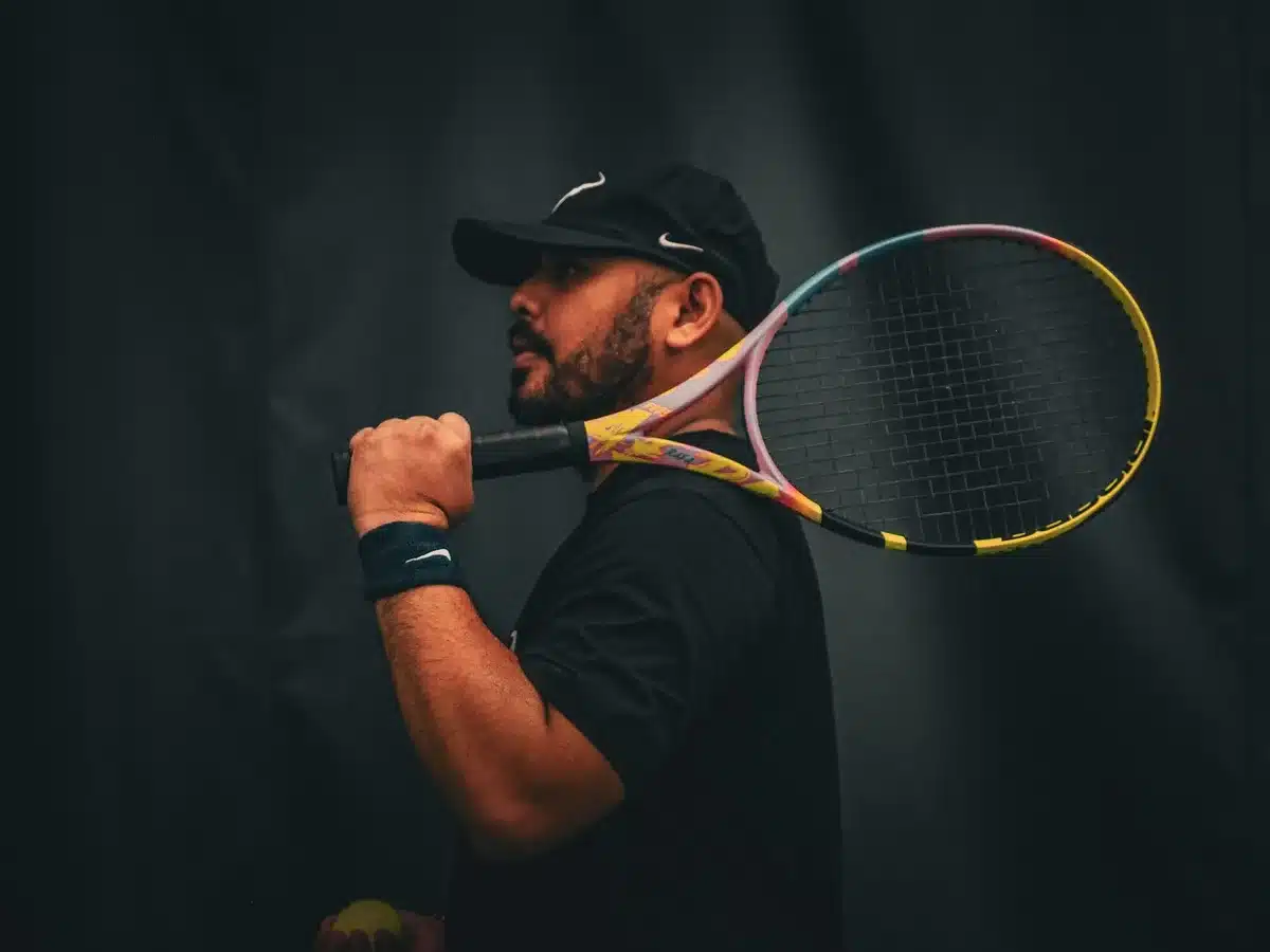 Close-up of a tennis racket and ball placed on a tournament draw sheet on a bench, no logos visible