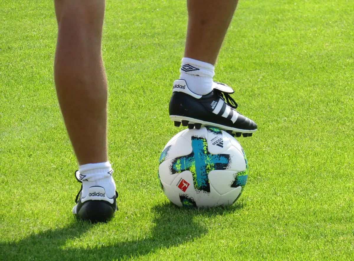 An empty, well-lit training pitch with a single corner flag and scattered cones, evoking preparation and anticipation before kickoff