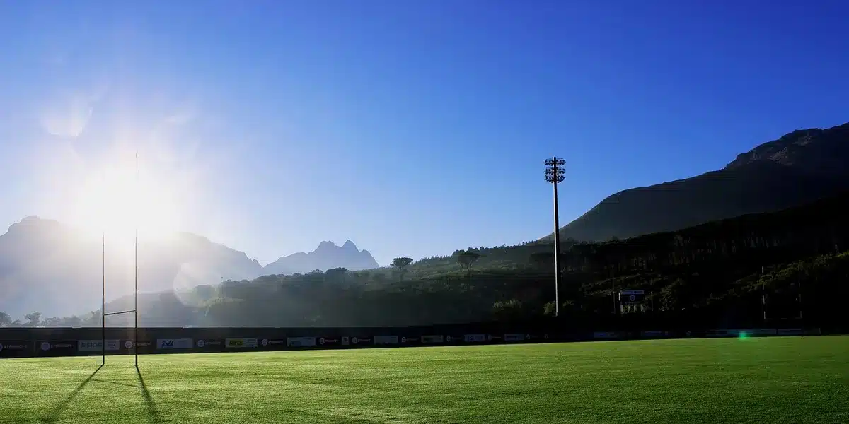 empty rugby pitch at dusk with a single set of goalposts and an abandoned jersey on the turf