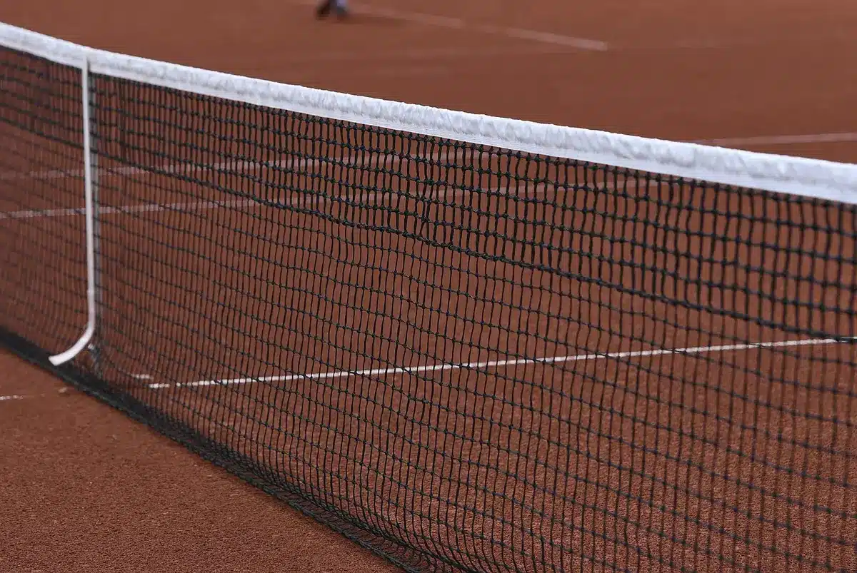 Close-up of a wooden volleyball court with a net in foreground and an empty bench in the background, no logos or people visible